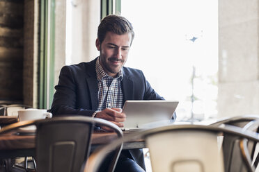 Businessman using tablet in a cafe - UUF09753