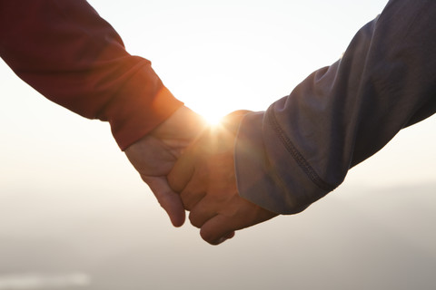 Pärchen Hand in Hand bei Sonnenuntergang, lizenzfreies Stockfoto