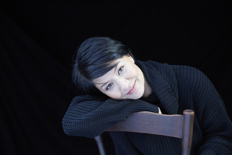 Porträt einer lächelnden Frau auf einem Stuhl, lizenzfreies Stockfoto