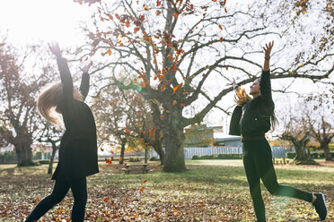Zwei glückliche junge Frauen haben Spaß im Park im Herbst - MGOF02759
