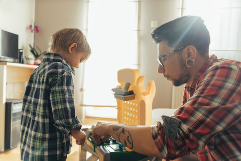 Vater und Sohn spielen zusammen auf einer Spielzeugwerkbank, lizenzfreies Stockfoto