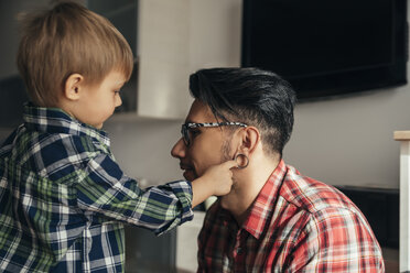 Son examining father's flesh tunnel - ZEDF00488