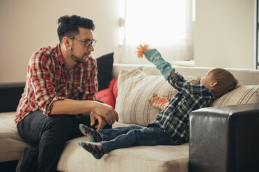 Father and son playing together on couch - ZEDF00489