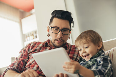 Father and son on couch using tablet - ZEDF00499