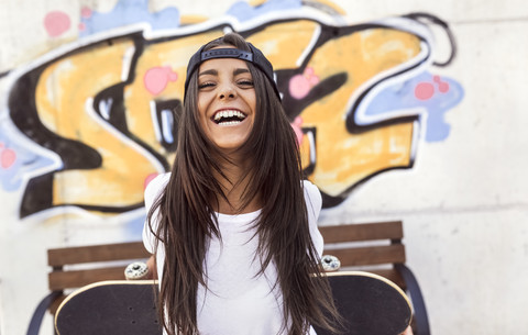 Laughing young woman holding skateboard stock photo