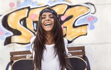 Laughing young woman holding skateboard - MGO02768