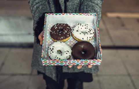 Frau hält Schachtel mit Doughnuts, Teilansicht, lizenzfreies Stockfoto