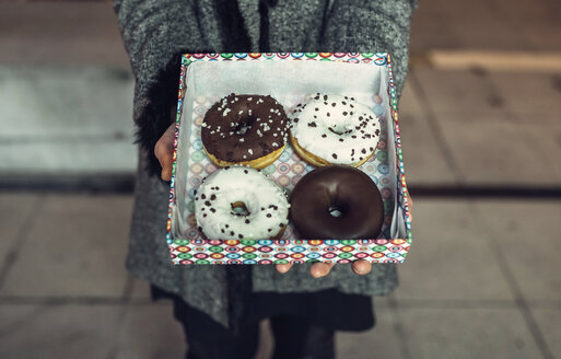 Woman holding box with doughnuts, partial view - DAPF00533