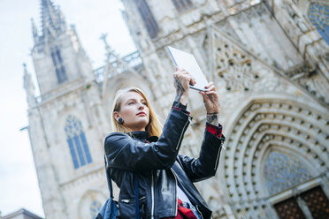 Spanien, Barcelona, junge Frau fotografiert mit Tablet vor der Kathedrale - KIJF01038