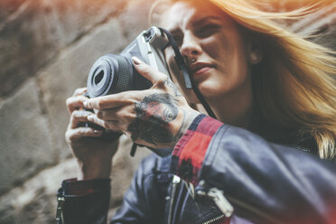 Tattooed woman's hands holding reflex camera - KIJF01042