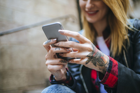 Tattooed woman's hands holding cell phone, close-up stock photo