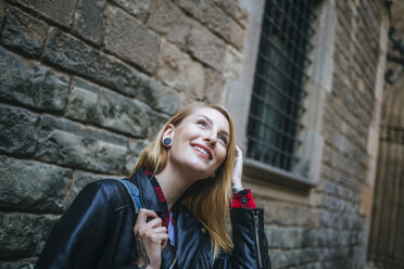 Spain, Barcelona, smiling young woman looking up - KIJF01049