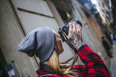 Spain, Barcelona, young woman taking pictures with reflex camera at Gothic Quarter - KIJF01059