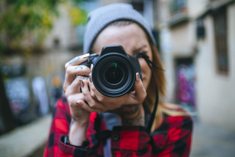 Junge Frau, die einen Betrachter mit einer Spiegelreflexkamera fotografiert, lizenzfreies Stockfoto