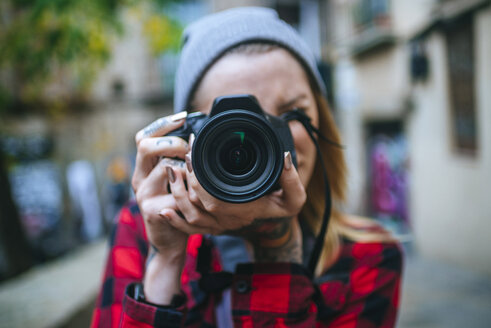 Junge Frau, die einen Betrachter mit einer Spiegelreflexkamera fotografiert - KIJF01065