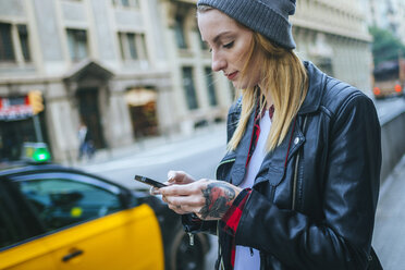 Spanien, Barcelona, junge Frau auf der Straße, die ihr Mobiltelefon benutzt - KIJF01070