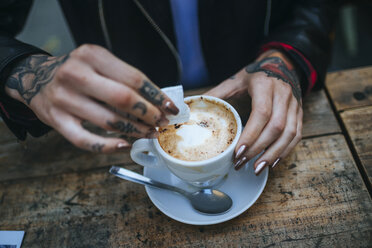 Tätowierte Hände einer Frau, die Zucker in eine Tasse Kaffee gießen, Nahaufnahme - KIJF01076