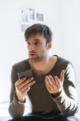 Junger Mann beim Telefonieren zu Hause - KKAF00292