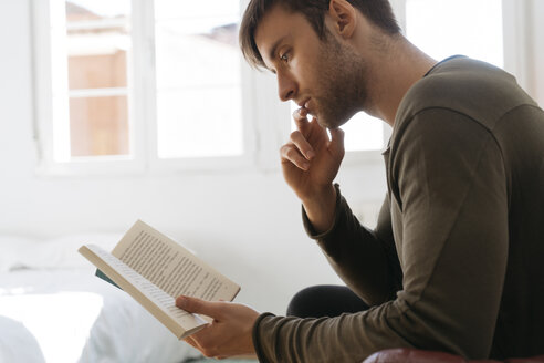 Junger Mann liest zu Hause ein Buch - KKAF00293