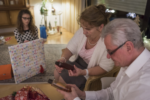 Gift giving at Christmas eve, grandparents looking at bottles stock photo