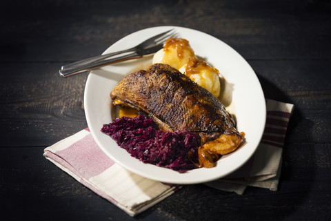 Teller mit gebratener Gänsebrust, Rotkohl und Kartoffelknödeln, lizenzfreies Stockfoto