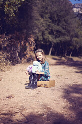 Porträt eines Mädchens, das auf einem alten Koffer sitzt - XCF00124