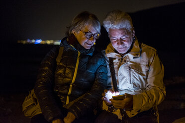 Senior couple using cell phone at night - SIPF01278