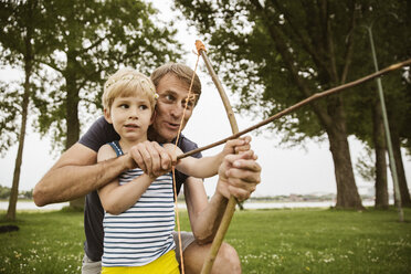 Vater und Sohn spielen mit selbstgebautem Pfeil und Bogen - MFF03423