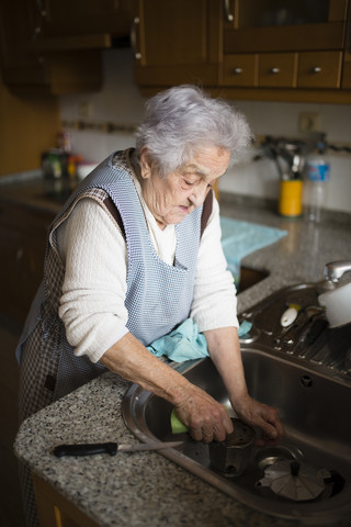 Ältere Frau wäscht Geschirr in der Küche, lizenzfreies Stockfoto