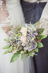 Close-up of bride and groom holding bridal bouquet - ASCF00691