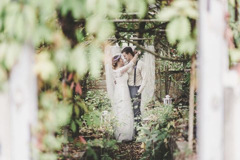 Braut und Bräutigam umarmen sich im Gewächshaus, lizenzfreies Stockfoto