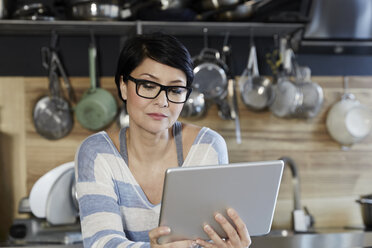 Frau in Küche schaut auf Tablet - FMKF03455