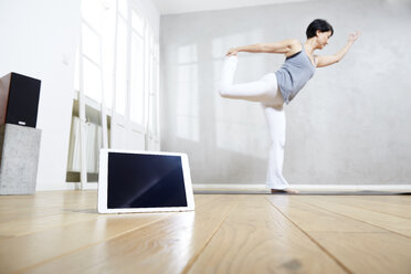 Frau übt Yoga hinter Tablet - FMKF03470