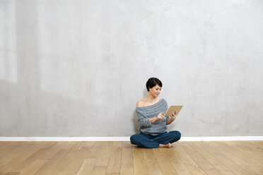 Woman sitting on floor using tablet - FMKF03477