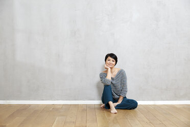 Portrait of woman sitting on floor - FMKF03478