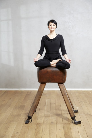 Frau übt Yoga am Pauschenpferd, lizenzfreies Stockfoto