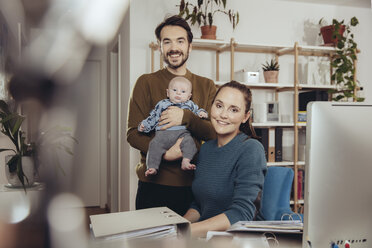 Porträt eines lächelnden Vaters und einer lächelnden Mutter mit Baby im Home Office - MFF03427
