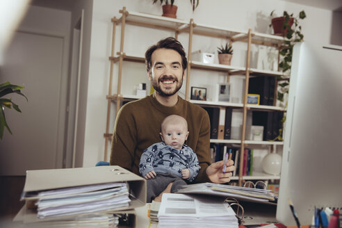 Porträt eines lächelnden Vaters mit seinem Baby im Heimbüro - MFF03428