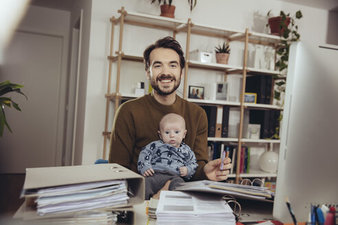 Portrait of smiling father with his baby in home office - MFF03428