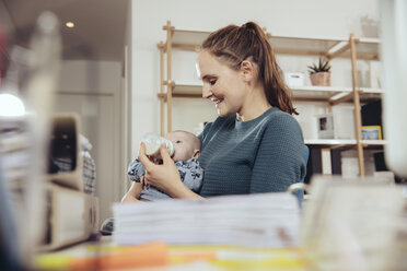 Woman feeding her baby in home office - MFF03432