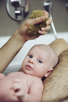 Vater und Baby nehmen ein Bad mit einem Naturschwamm - MFF03442