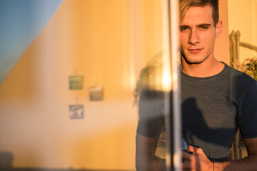 Portrait of young man with glass of red wine at sunset on balcony - SIPF01306