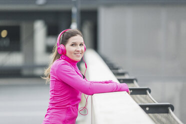 Portait of smiling sportive woman wearing headphones - ASCF00709