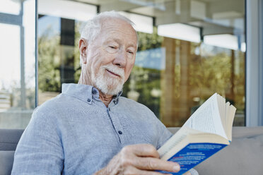 Älterer Mann sitzt auf der Terrasse und liest ein Buch - RORF00437