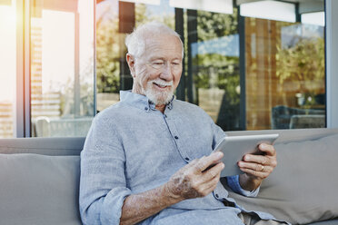 Älterer Mann sitzt auf der Terrasse und liest ein ebook - RORF00438