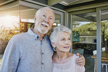 Senior couple standing in front of their house, looking confident - RORF00444