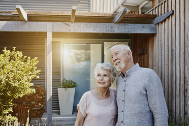 Ein älteres Ehepaar steht vor seinem Haus und sieht zuversichtlich aus - RORF00447