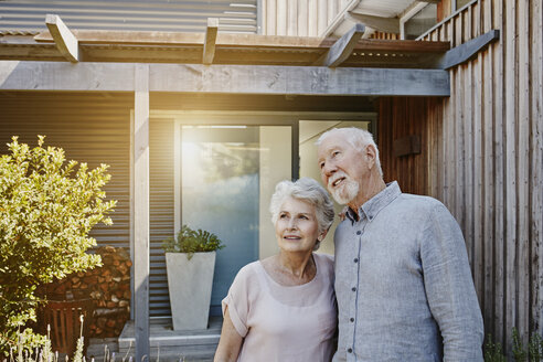 Senior couple standing in front of their house, looking confident - RORF00447