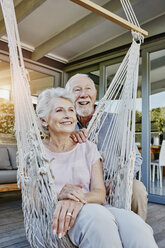 Senior couple on terrace, woman sitting in hammock - RORF00448