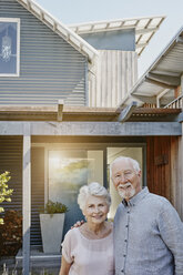 Ein älteres Ehepaar steht vor seinem Haus und sieht zuversichtlich aus - RORF00449